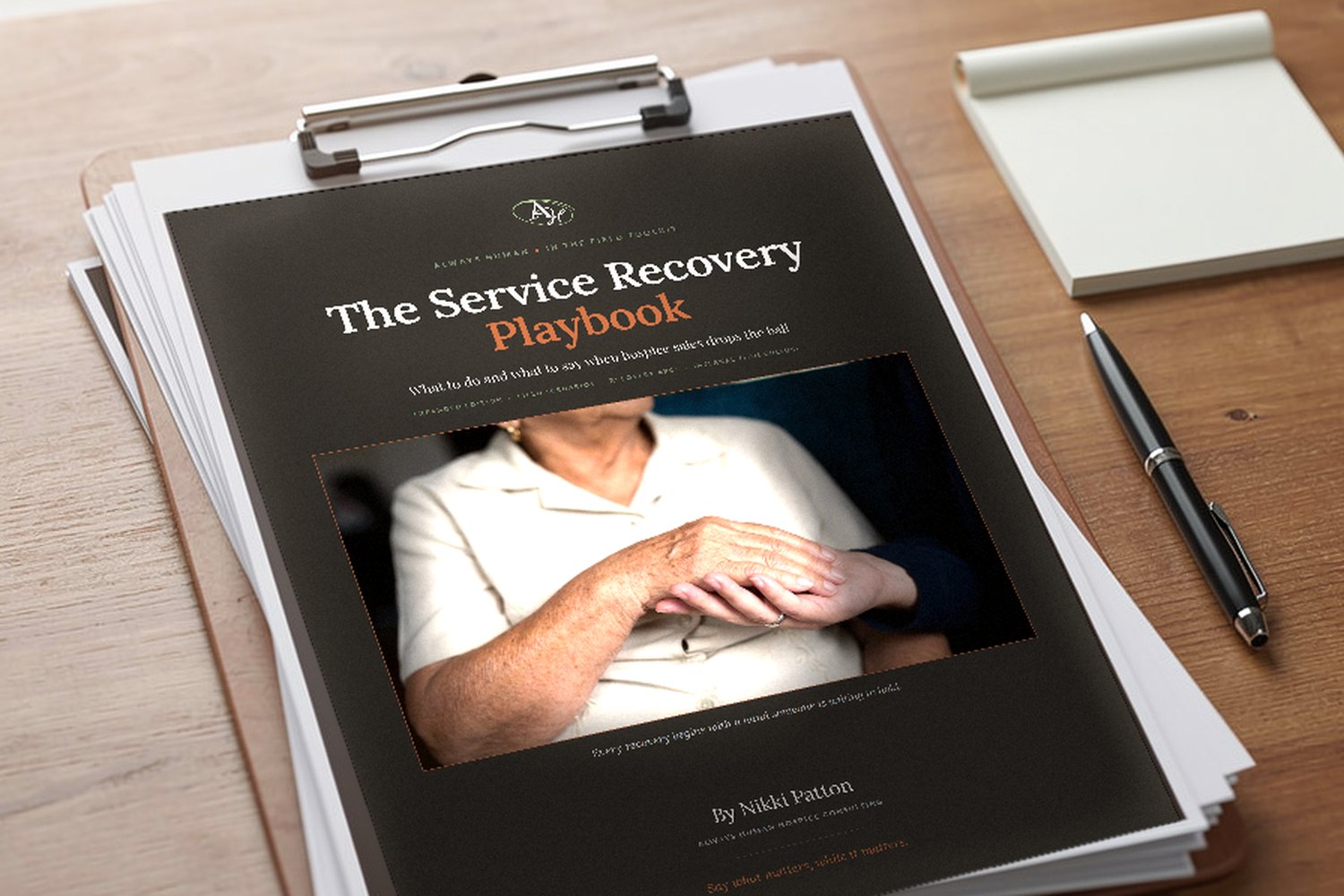 The Service Recovery Playbook on a clipboard beside a notepad and pen